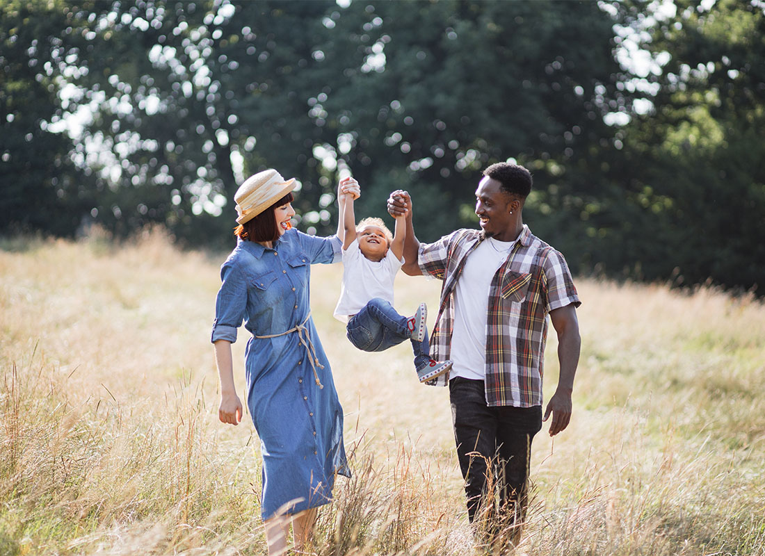 Read Our Reviews - Portrait of Two Cheerful Parents Holdng Up Their Daughter in the Air During a Walk Through a Field of Tall Grass in the Countryside on a Summer Day