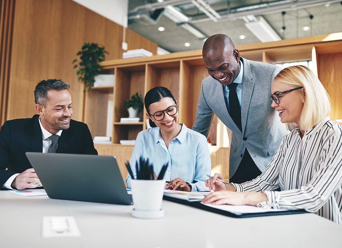 About Commercial Insurance - Business Professionals Discussing and Standing Around Talking While at a Conference Table in a Modern Office